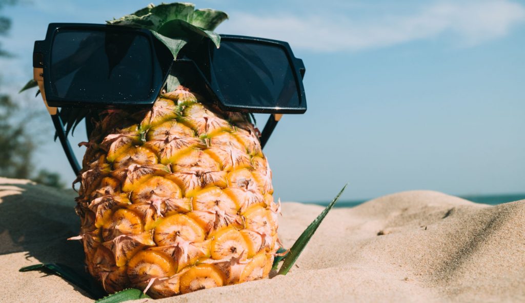 pineapple in sand with shades on. Anchor monkey Digital Marketing Web Design, SEO, Logo Design in Antigua and Barbuda, Commonwealth of Dominica, Grenada, Montserrat, St. Kitts and Nevis, Saint Lucia and St. Vincent and the Grenadines